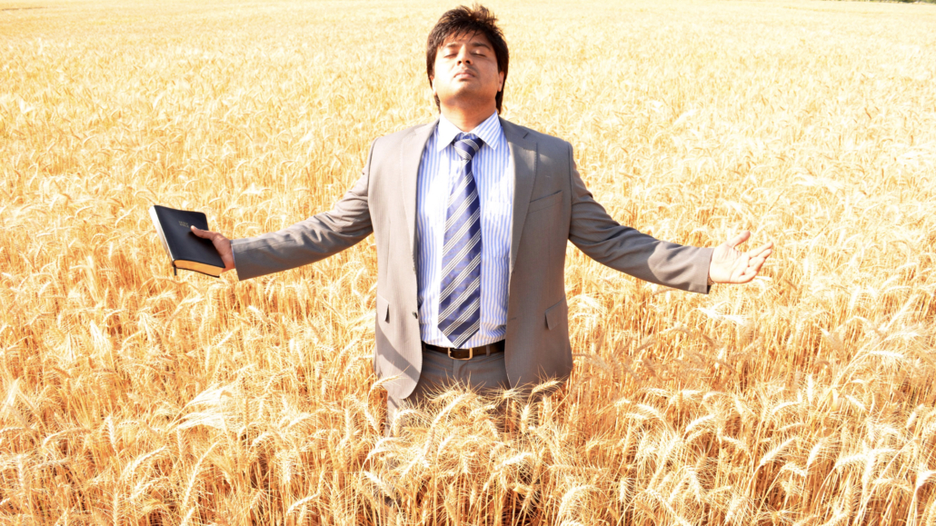 Rev. Dr. Naeem Nasir in a wheat field with the Bible, the vision of Church Planting in Pakistan